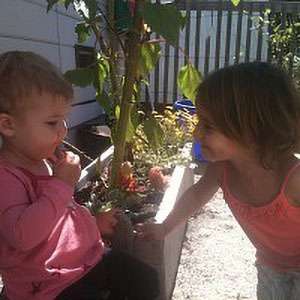 girl in pink shirt leaning in to talk to a smaller child