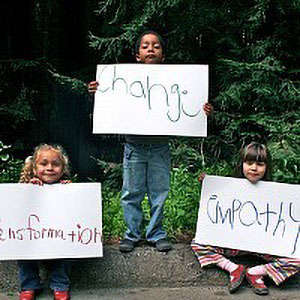 young students holding signs that read “transformation,” “change,” and “empathy”